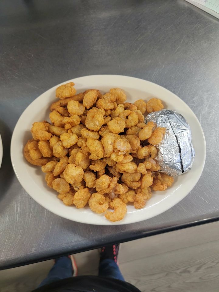 Plate of fried popcorn shrimp with a baked potato